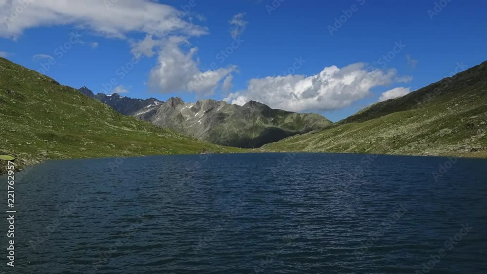 Time lapse view on peak of mountains and lake in Swiss Alps. Summer landscape, sunshine weather, blue sky and sunny day Time lapse view on peak of mountains and lake in Swiss Alps. Summer landscape, sunshine weather, blue sky and sunny day
