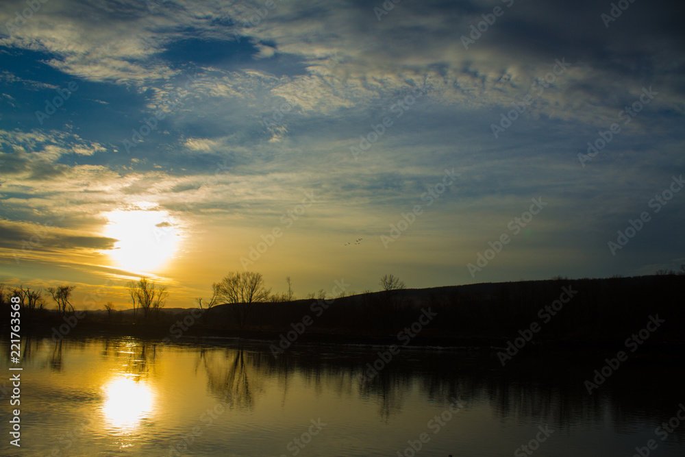 Obraz premium Bright Orange Sunset Over Calm River 