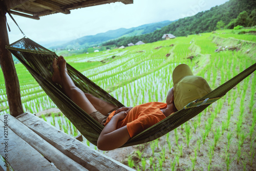 Asian woman travel nature. Travel relax. Relax in the hammock the balcony of the resort. View of the field on the Moutain in summer. Thailand