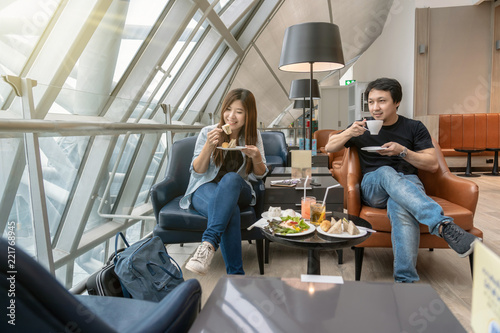 Asian couple sitting and eatting inn airport lounge when waiting the flight at modern international airport, travel and transportation concept