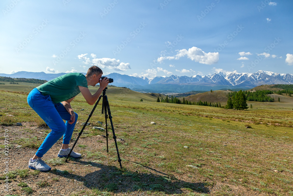 Travel  hiking man shoooting  mountain landscape. Tourist professional photographer on  vacation shooting,   camera on tripod.