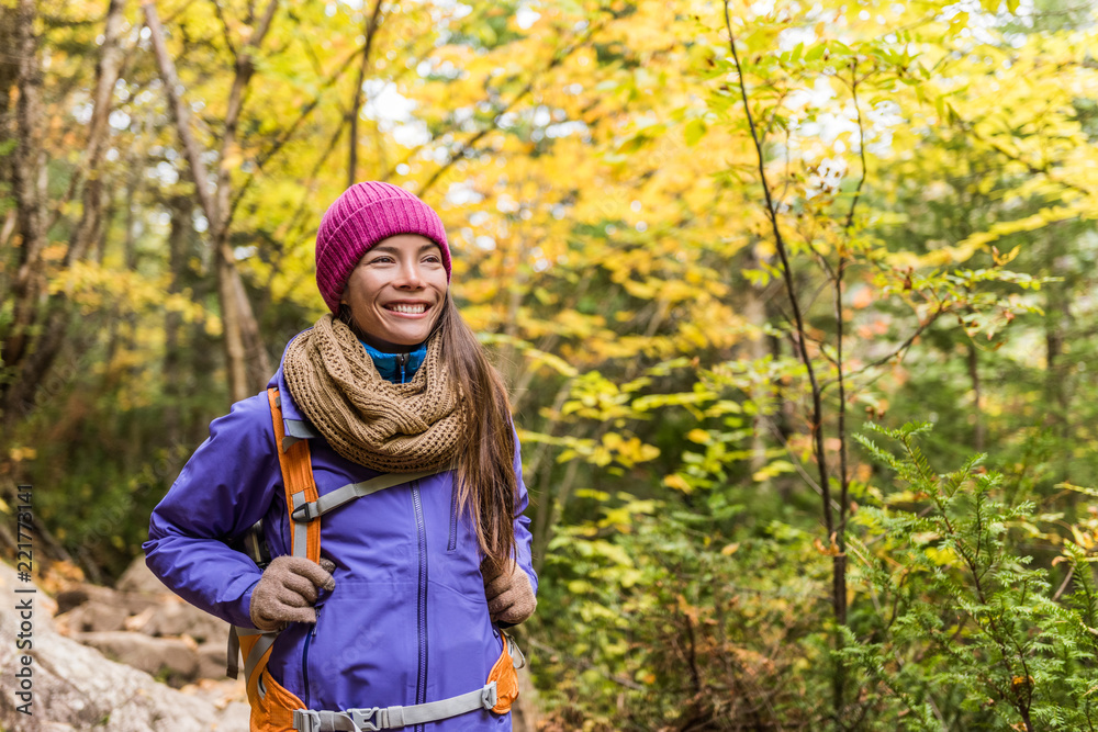 Happy asian woman hiking in autumn forest nature walking on trail path. Hiker  girl with backpack