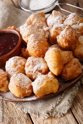 Albanian traditional food: fried dough petulla with raspberry jam and powdered sugar close-up on the table. vertical