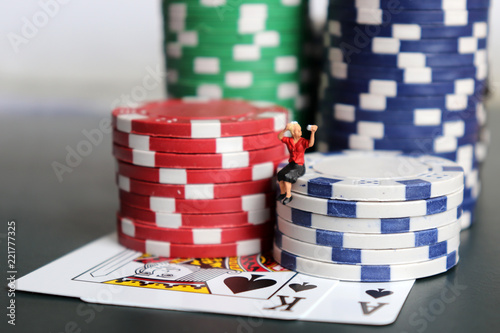 A miniatures woman sitting wearing makeup on a pile of casino chips with cards. photo