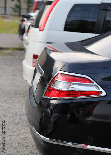 Closeup of rear side of black car park in parking area. Vertical view. © Amphon