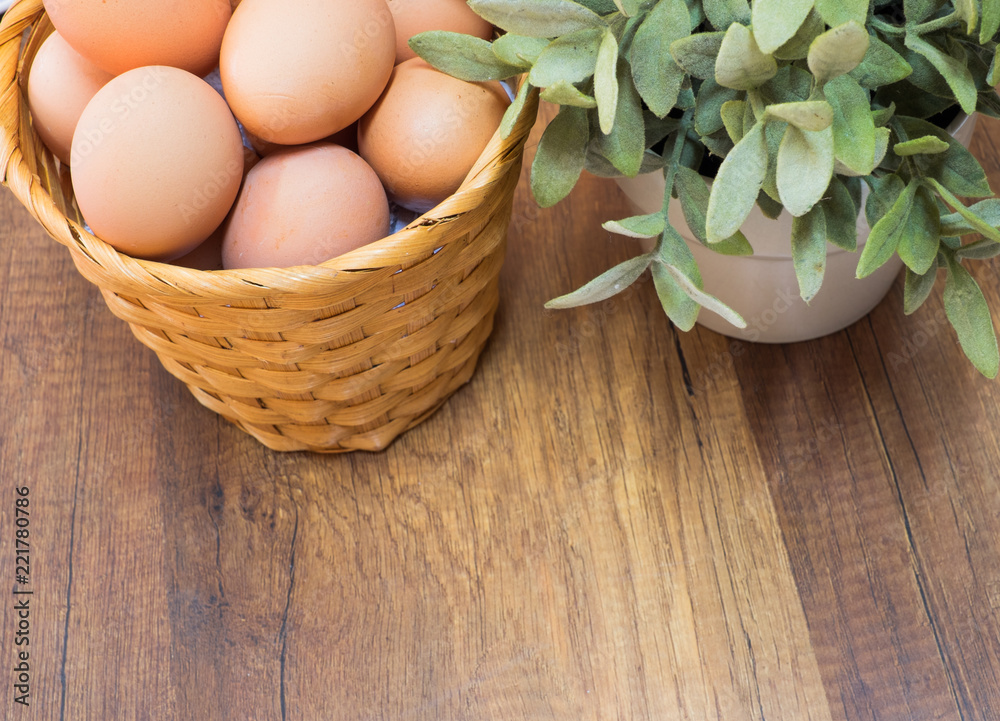 Fresh chicken eggs in basket on wooden table with space for text