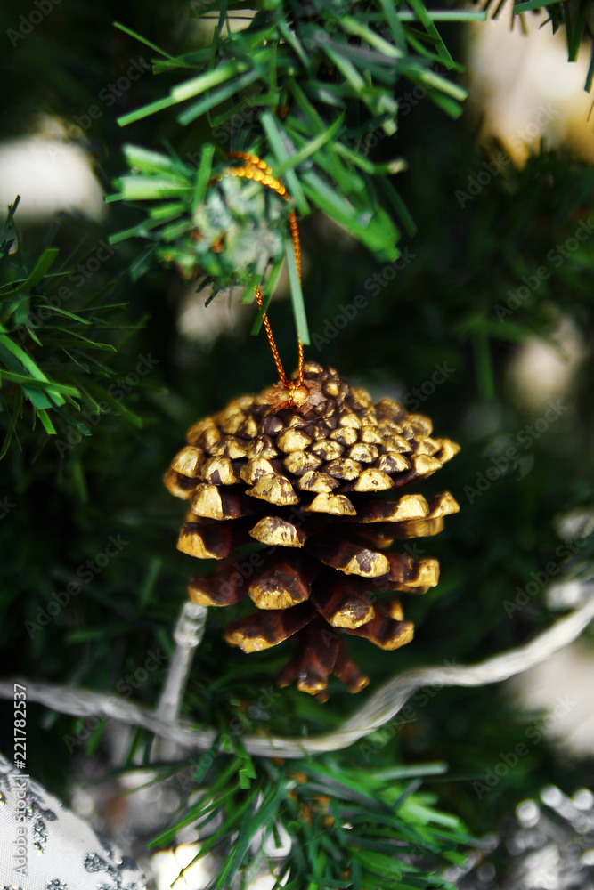 Obraz premium Pine cone decorated of shiny golden paint on a fir tree. Christmas and New Year decorations.