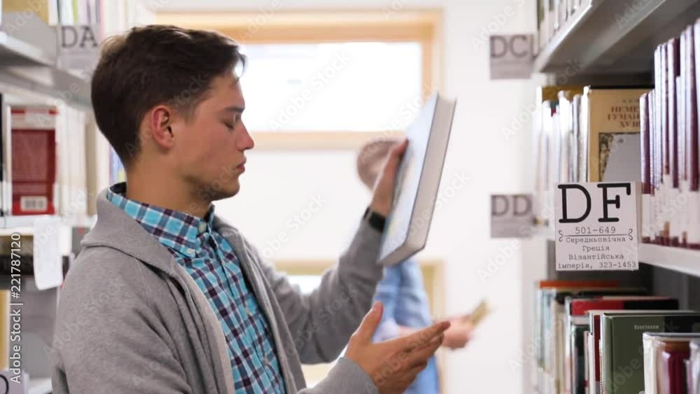 Student At Library. Man Looking Books On Bookshelves