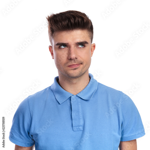 young casual man thinks and looks up to side