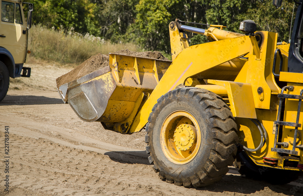 Tractor loader on the river bank performs the loading of gravel into the car body Tractor loader on the river bank performs the loading of gravel into the car body