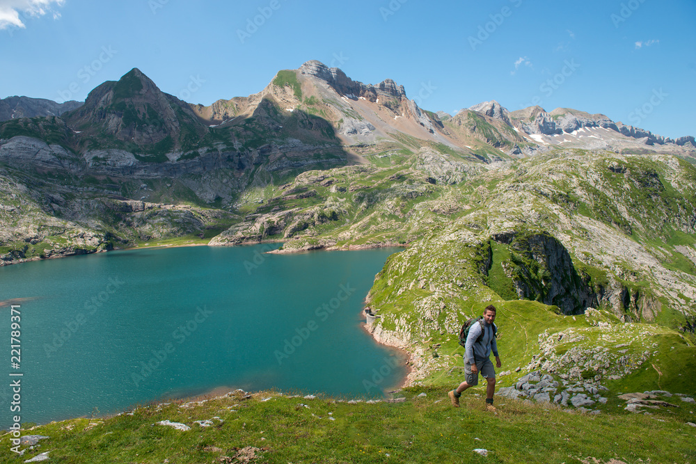 man hiker climbing a slope, Lake Estaens in the background