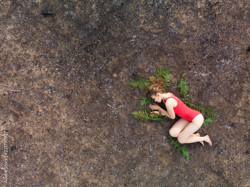 A woman lies on the fern leaves on the burnt ground