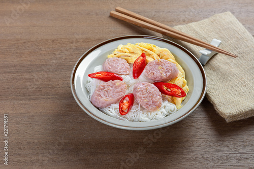 rice vermicelli with fermented pork sausage and omelette in a ceramic dish on wooden table. asian homemade style food concept.