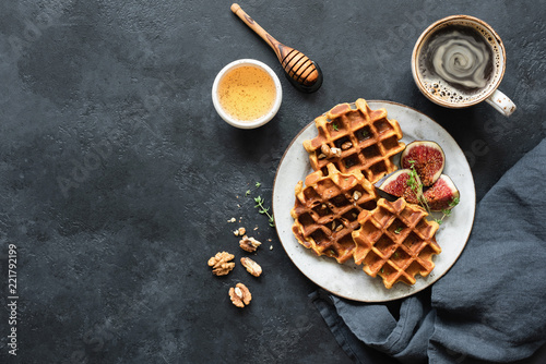 Whole wheat waffles with honey and figs on black concrete background. Top view, copy space for text photo