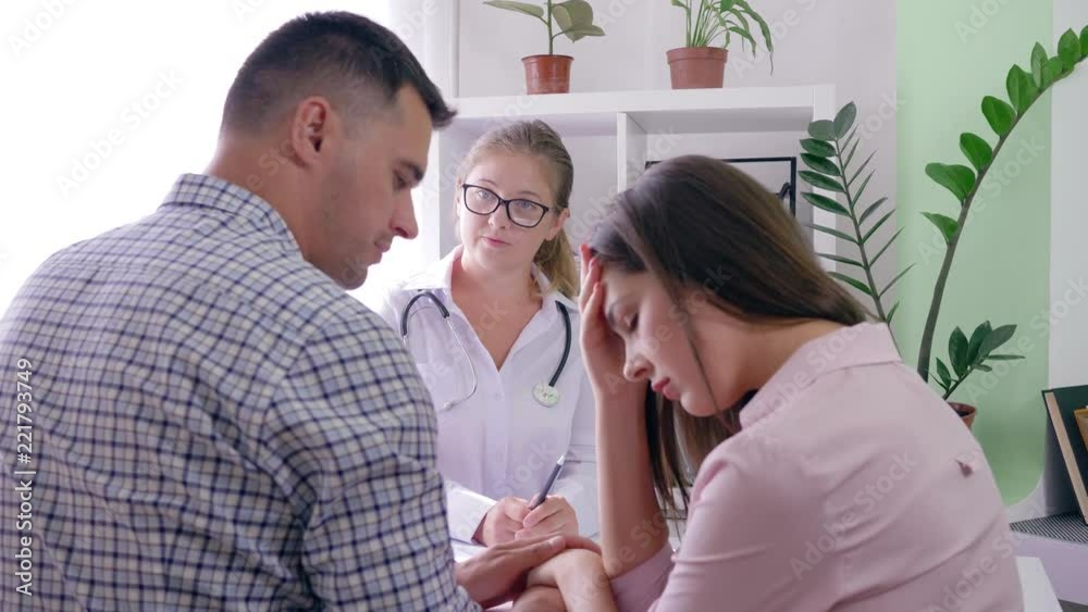 women health, doctor speaks about bad results of the analysis to a upset married couple on reception in an office