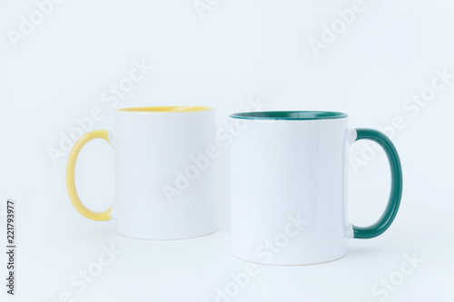 Two white mugs, with a green and yellow handle on a white background. Isolated. 