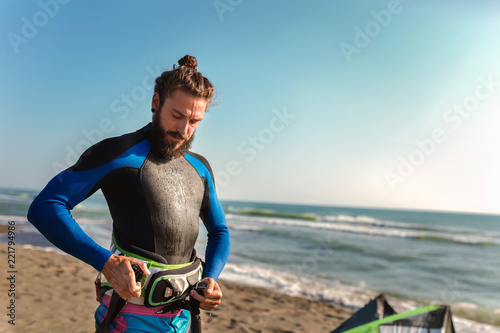Man sufrers in wetsuits with kite equipment for surfing.