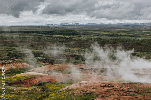 aerial view landscape with volcanic vents under cloudy sky in Haukadalur valley in Iceland