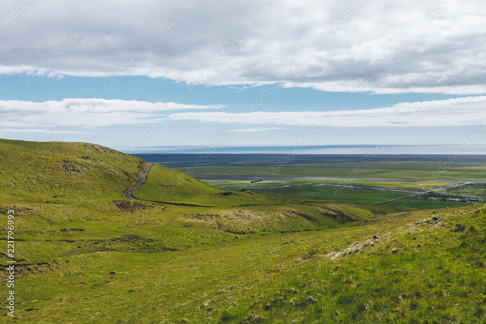 scenic view of landscape with green highlands under cloudy blue sky in Iceland