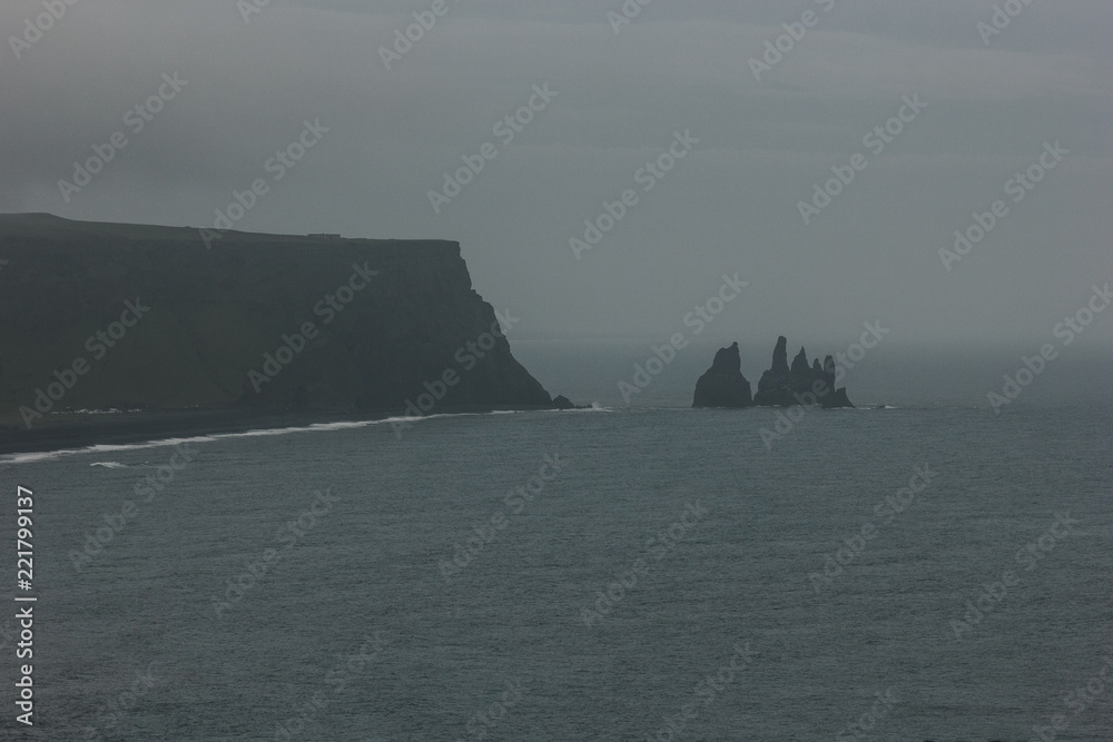 rocky cliff and ocean under cloudy sky at Dyrholaey promontory in Vik, Iceland rocky cliff and ocean under cloudy sky at Dyrholaey promontory in Vik, Iceland