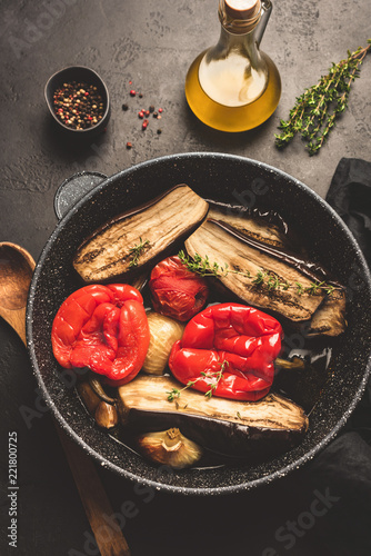 Oven roasted vegetables on pan. Roasted eggplant, red bell pepper, onion, garlic and tomato. Healthy vegetarian food. Top view, toned image