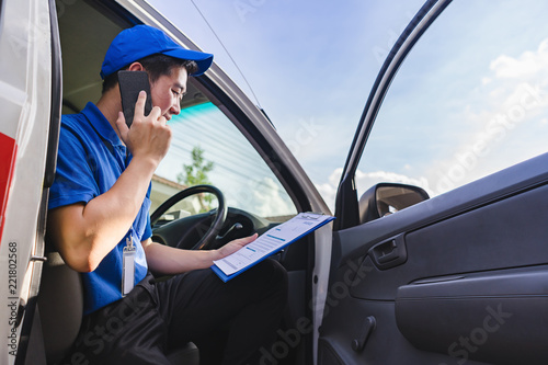 Fotografía Delivery man sitting on van seat and calling to customer