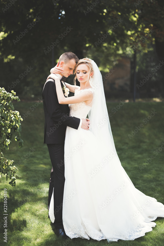 Lovely happy wedding couple, bride with long white dress posing in beautiful city Lovely happy wedding couple, bride with long white dress posing in beautiful city