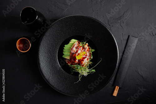 top view of Japanese Ceviche with seafood, avocado and herbs on black plate