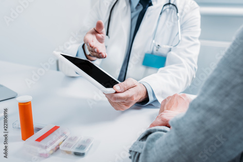 Wallpaper Mural partial view of male doctor pointing at digital tablet with blank screen to female patient at table in office Torontodigital.ca