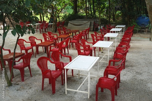 Outdoor jungle cafe with red chairs and white tables in Southeast Asia