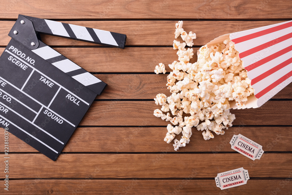 Fototapeta premium Popcorn tickets and clapperboard on wooden table