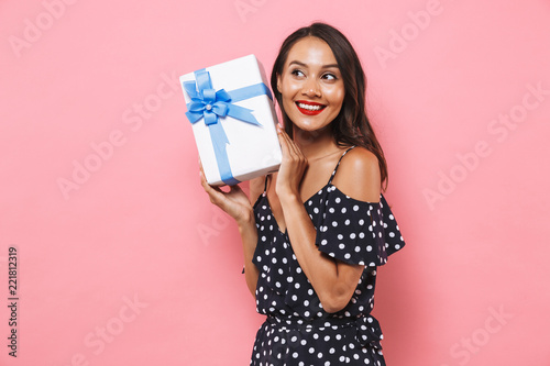 Woman isolated over pink background holding susprise gift box.