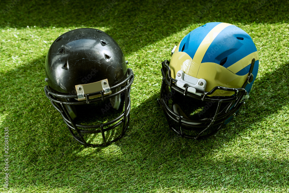 Naklejka high angle view of american football safety helmets on green grass
