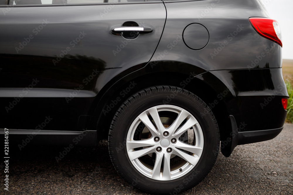 Car wheel close-up. Black modern car closeup. Car wheel close-up. Black modern car closeup.