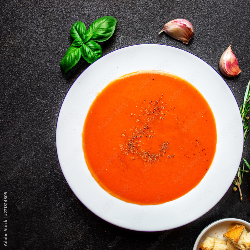 Tomato Soup with herbs on black slate table. Fresh homemade cream of Tomatoes soup with a swirl of cream. Top view. Tomato Soup with herbs on black slate table. Fresh homemade cream of Tomatoes soup with a swirl of cream. Top view.