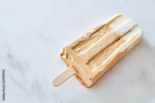Coffee and chocolate popsicle against a marble background with copy space