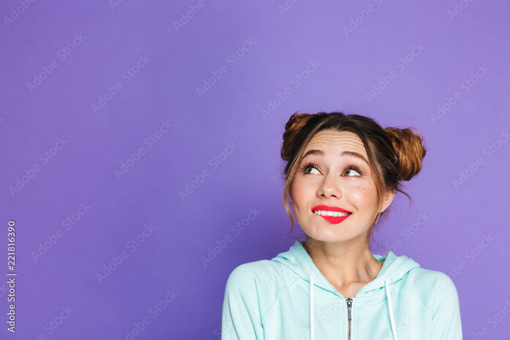 Portrait of adorable woman with two buns looking upward on copyspace and biting lip, isolated over violet background in studio Portrait of adorable woman with two buns looking upward on copyspace and biting lip, isolated over violet background in studio