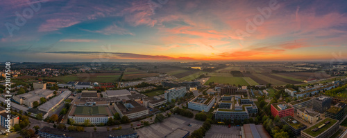 Sonnenaufgang in Bayern, Unterföhring im morgendlichen Glow zur aufgehenden Sonne mit einem Industriegebiet für Medien und einem See im Hintergrund