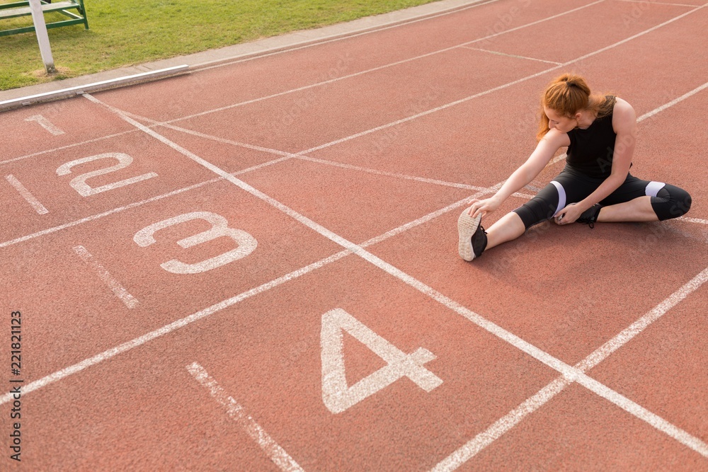 Female athletic exercising on running track Female athletic exercising on running track
