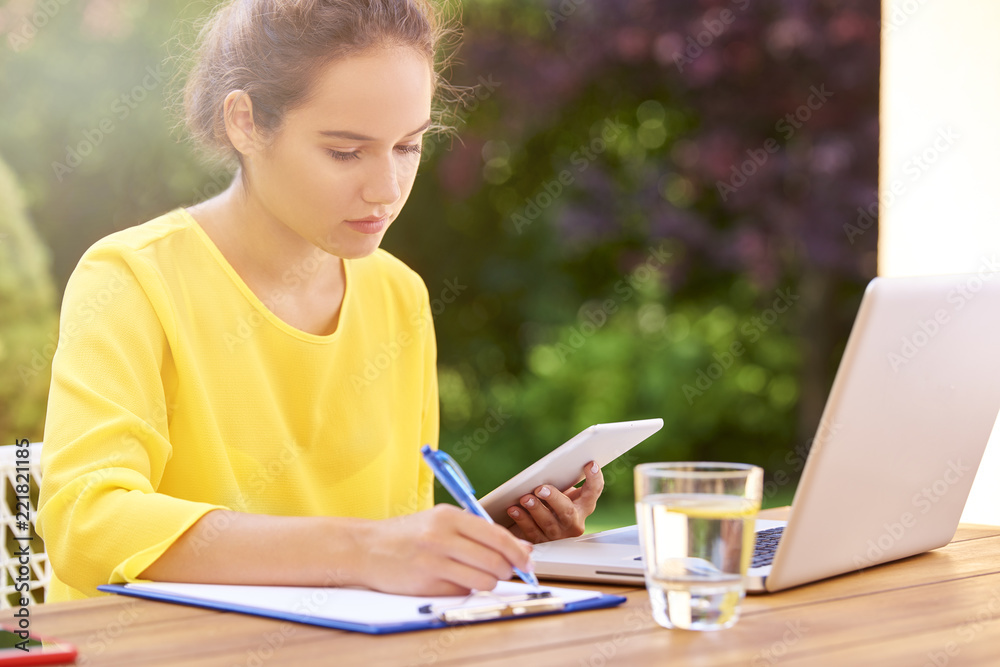 Happy young woman learning at home and using laptop outdoors at garden Happy young woman learning at home and using laptop outdoors at garden