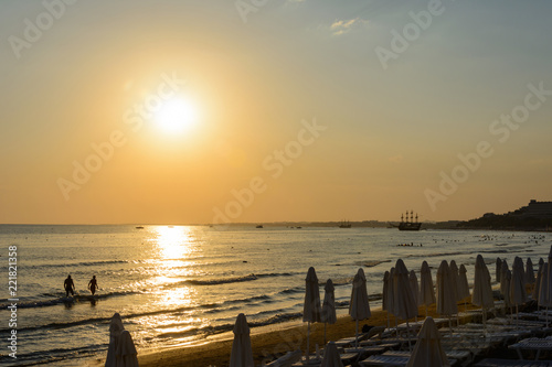 empty sea beach at sunset. folded umbrellas. boats on the horizon. vanilla tones