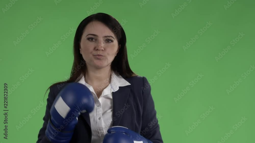 Slow motion of serious business woman with boxing gloves ready to fight against green screen Slow motion of serious business woman with boxing gloves ready to fight against green screen