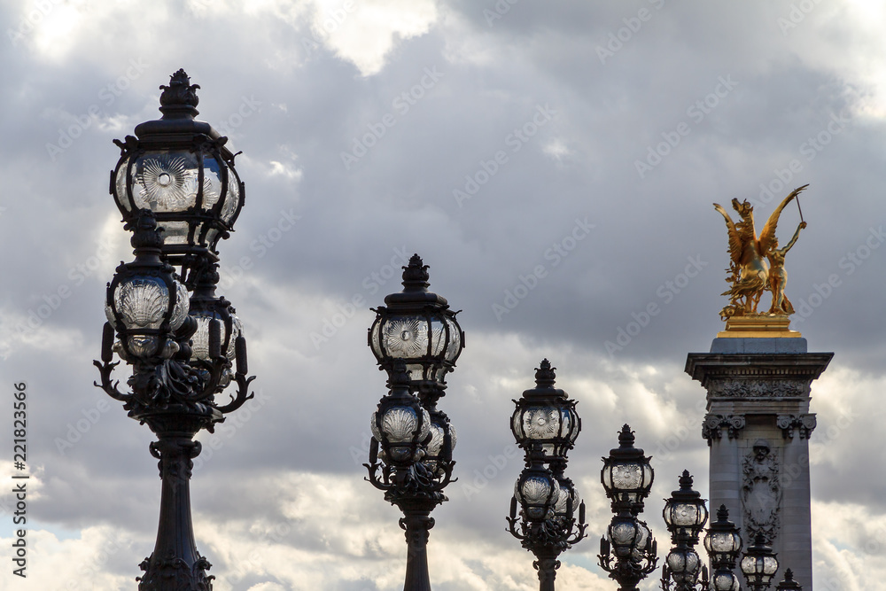 Lanterns on the Pont Alexandre III against a cloudy sky in Paris 