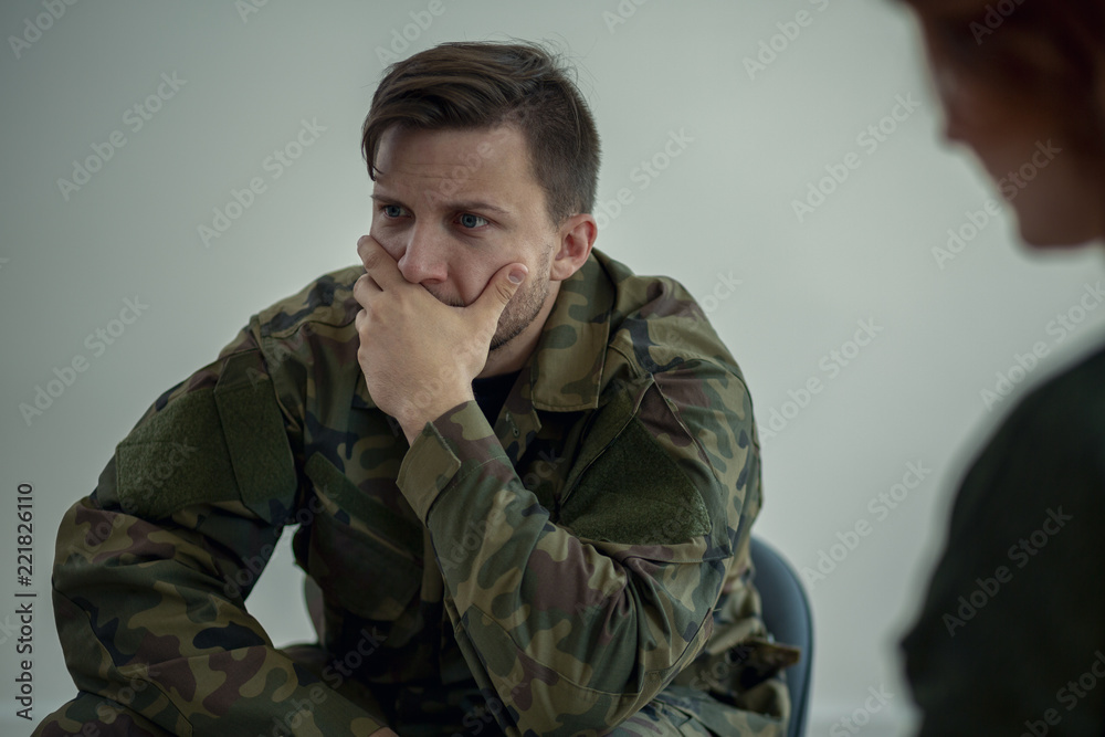 Terrified soldier in green uniform during meeting with psychotherapist