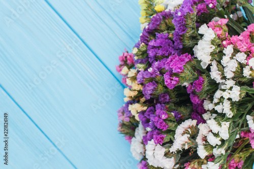Bouquet of limonium flowers on wood, close up. Copyspace, free space for text. Blue wooden table background.