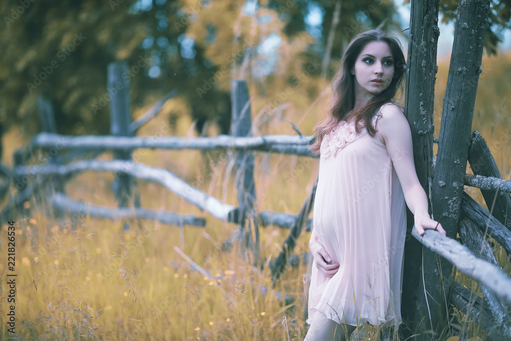 Naklejka premium Pregnant girl in a dress in nature