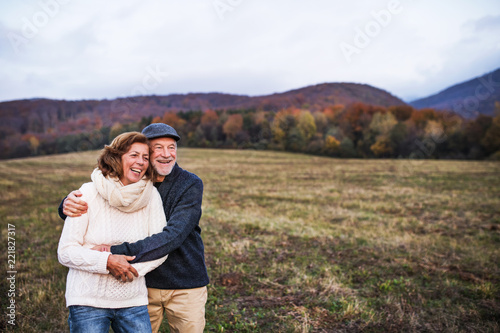 Senior couple hugging in an autumn nature at sunset, laughing.