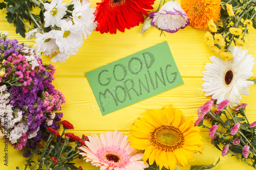 Lovely good morning wish and flowers. Yellow wooden desk background. photo