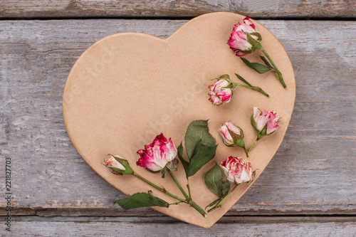 Fototapeta Naklejka Na Ścianę i Meble -  Heart-shaped cardboard and rose flowers. Old wooden background.