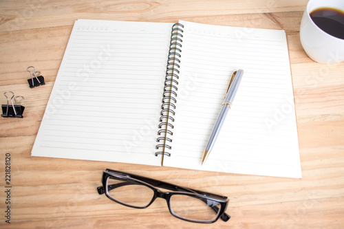 On the brown wood table there is a pen and notebook ready for work.
